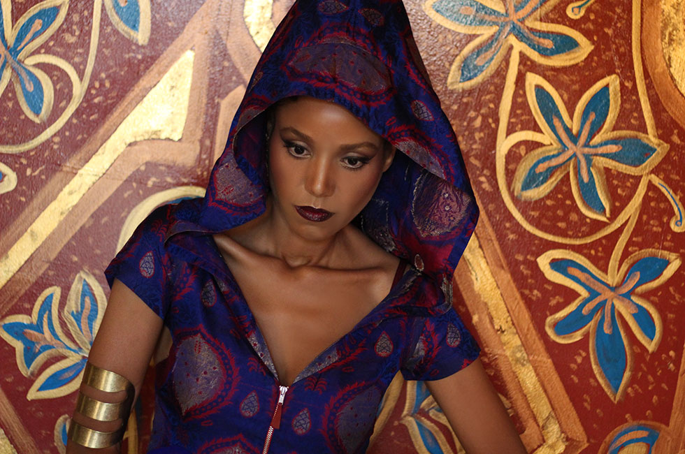 The Global Girl Editorials: Ndoema sports a silk hooded dress, tribal upper arm bracelet and pyramid studded two finger ring against vibrant gold Moroccan frescoes.