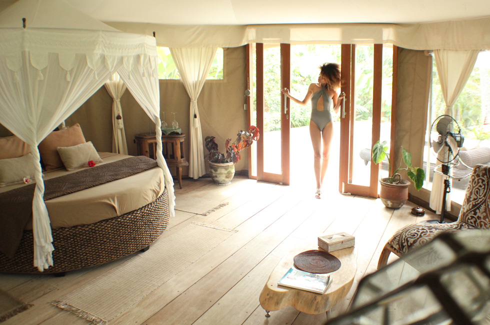 The Global Girl Travels: Ndoema at Tenda Penjor, a luxury safari-themed eco-chic glamping tent in Ubud, Bali. Featuring beautiful rattan canopy bed with tassel curtains and eco-friendly wood furniture by local Balinese artists and artisans.